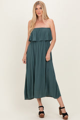 woman wearing a teal strapless maxi dress with a ruffled layer and flowing silhouette