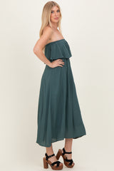woman wearing a dark green off-shoulder maxi dress with a ruffle detail and standing in profile