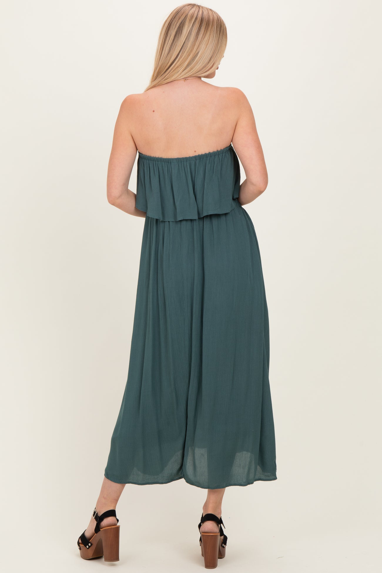 woman wearing a teal off-the-shoulder maxi dress with a tiered ruffled bodice and flowing silhouette