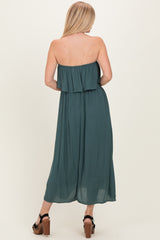 woman wearing a teal off-the-shoulder maxi dress with a tiered ruffled bodice and flowing silhouette