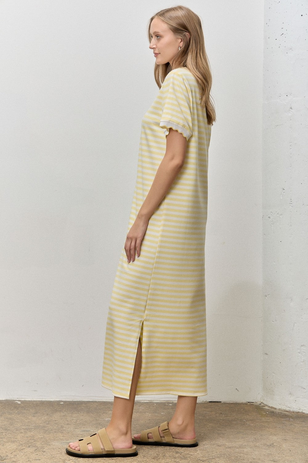 woman wearing a yellow and white striped midi dress with short sleeves and side slit