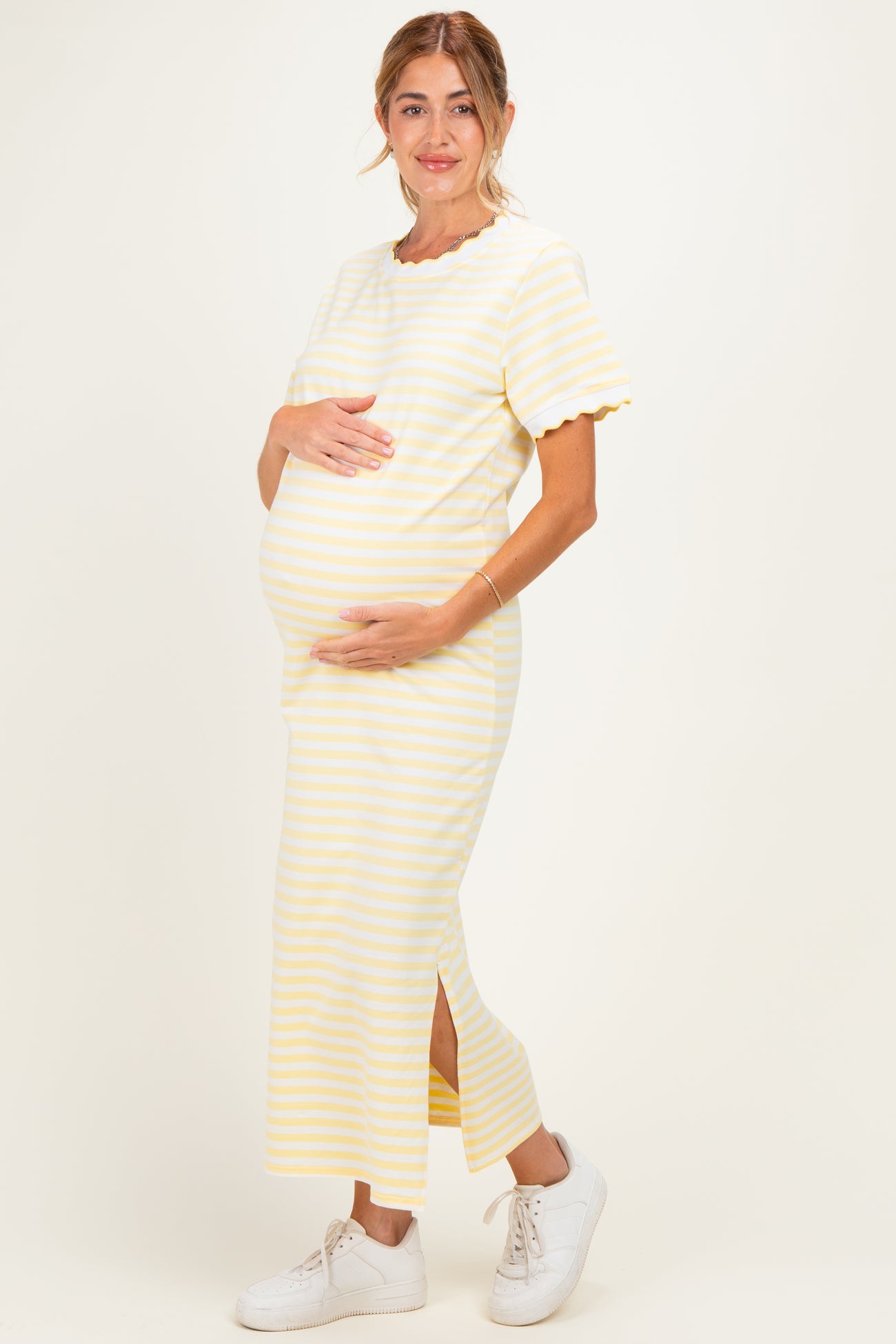 woman wearing a yellow and white striped maternity dress with short sleeves and a side slit, showing her baby bump