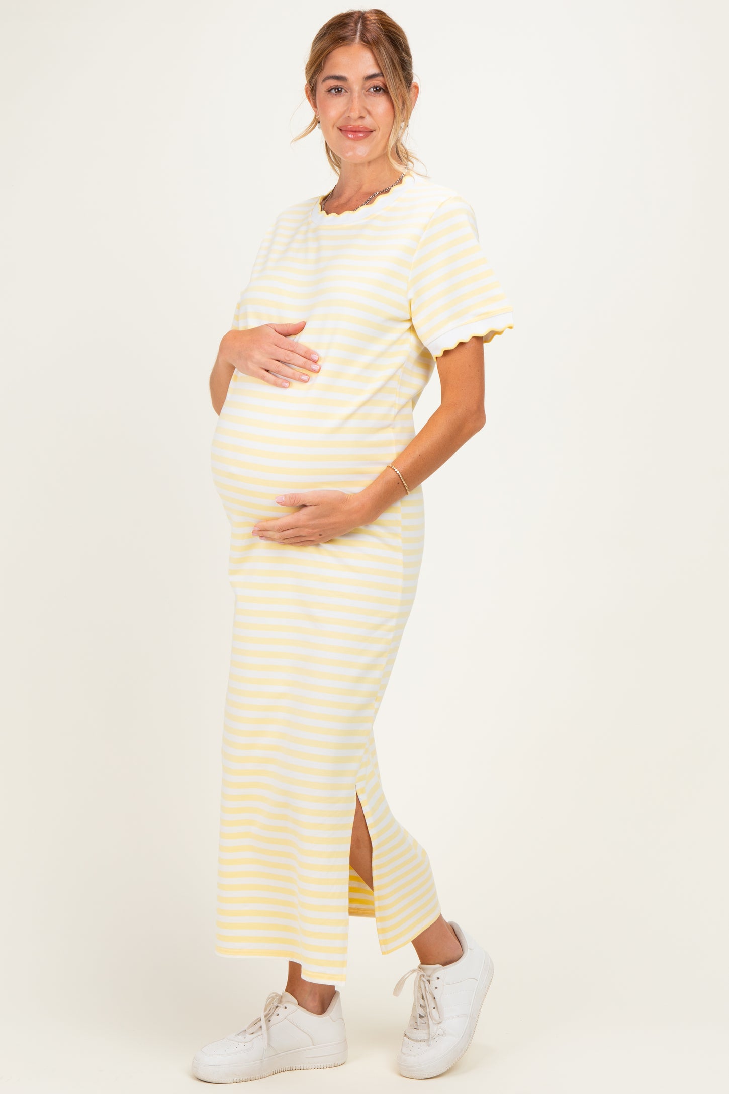 woman wearing a yellow and white striped maternity dress with short sleeves and a side slit, showing her baby bump