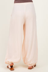 woman wearing light pink maternity pants with a relaxed fit and elastic cuffs at the ankles
