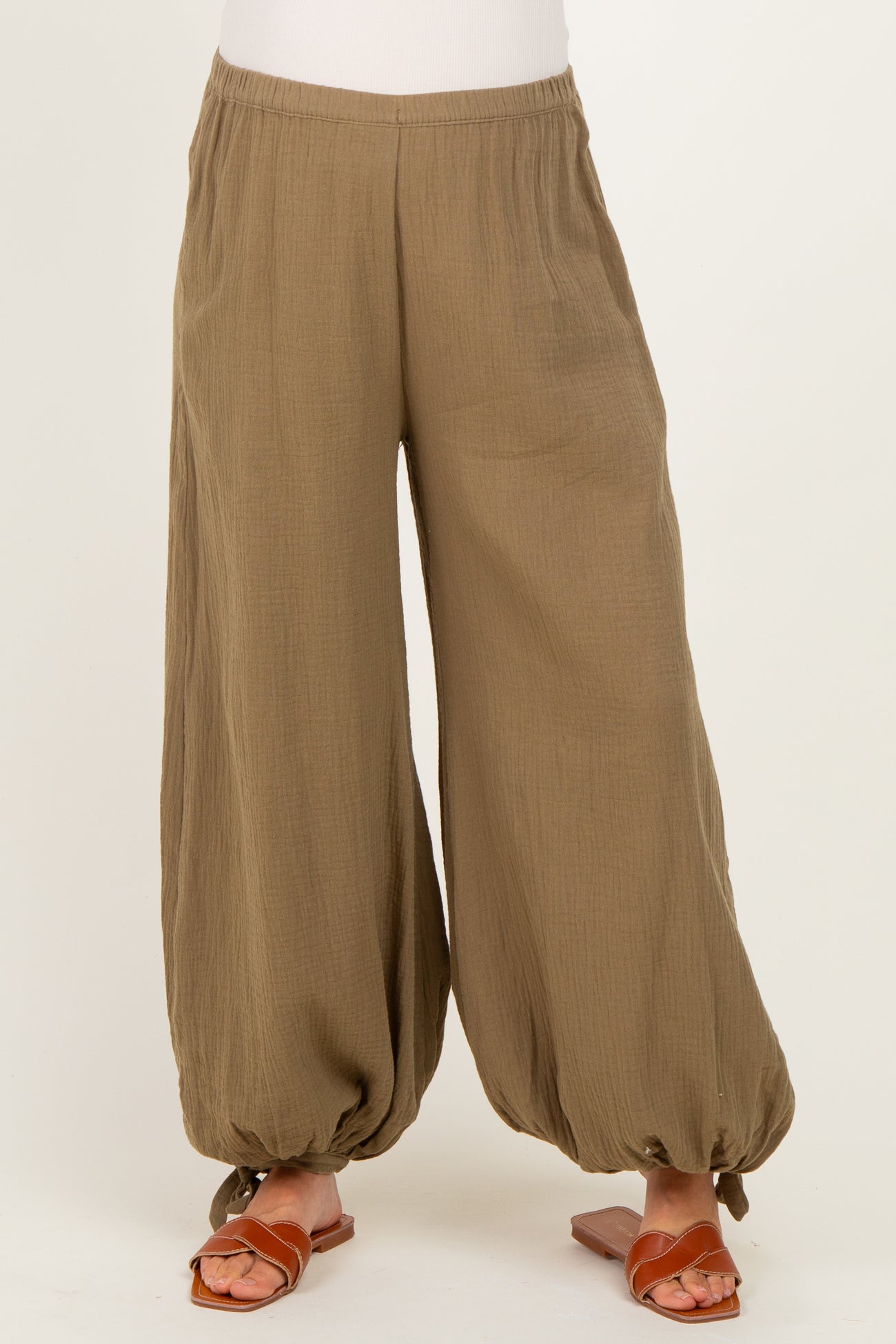 maternity wear in olive green wide-leg pants with gathered ankles, styled with brown sandals
