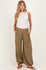 woman wearing a white tank top and olive green maternity wide-leg pants with side pockets and drawstring hems