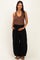 woman wearing a brown ribbed maternity tank top and black maternity wide-leg pants, holding her baby bump