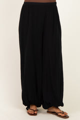 woman wearing black maternity harem pants with a loose fit and gathered cuffs, styled with brown sandals