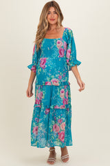 woman wearing a teal floral maternity maxi dress with smocked bodice and tiered ruffle sleeves