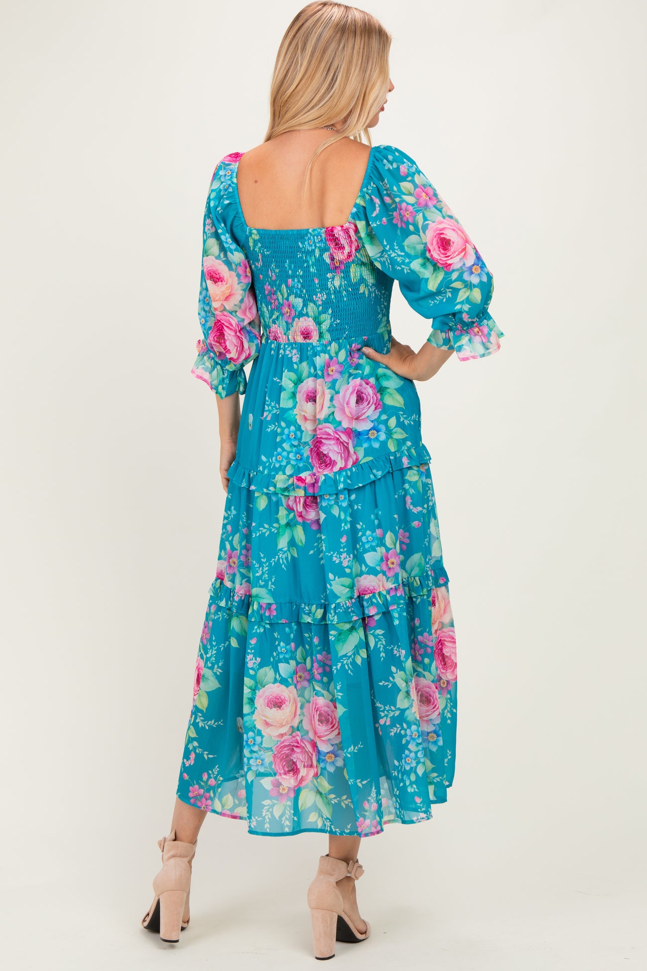 woman wearing a blue floral maxi dress with puff sleeves and a smocked bodice, showing a tiered design and back view
