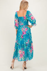 woman wearing a blue floral maxi dress with puff sleeves and a smocked bodice, showing a tiered design and back view