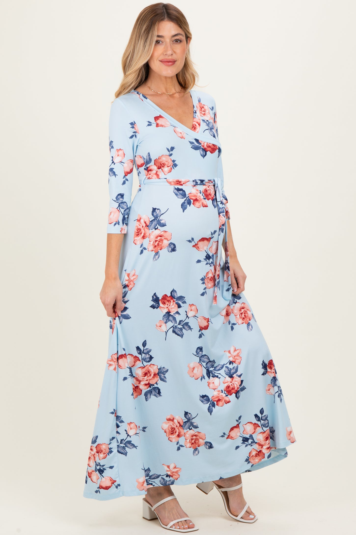 woman wearing a light blue floral maternity maxi dress with a wrap style and a baby bump visible