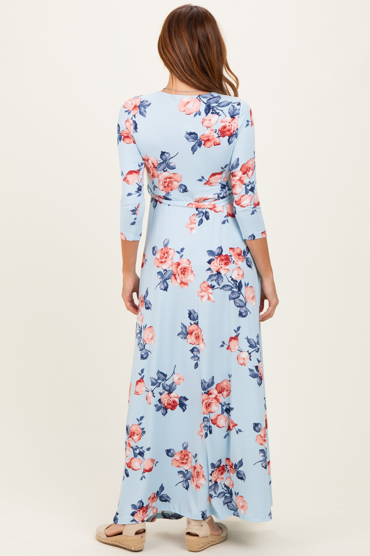 woman wearing a light blue floral maxi dress with three-quarter sleeves, showing the back view