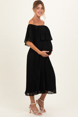 woman wearing a black pleated off-the-shoulder maternity dress and showing her baby bump
