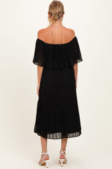 woman wearing a black off-the-shoulder pleated maternity dress, showing the back view and flowing hemline