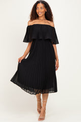 woman wearing a black off-shoulder pleated midi dress with ruffle details and strappy sandals