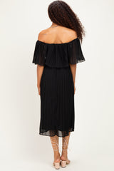 woman wearing a black off-the-shoulder pleated dress with flutter sleeves and a flowy, mid-length skirt