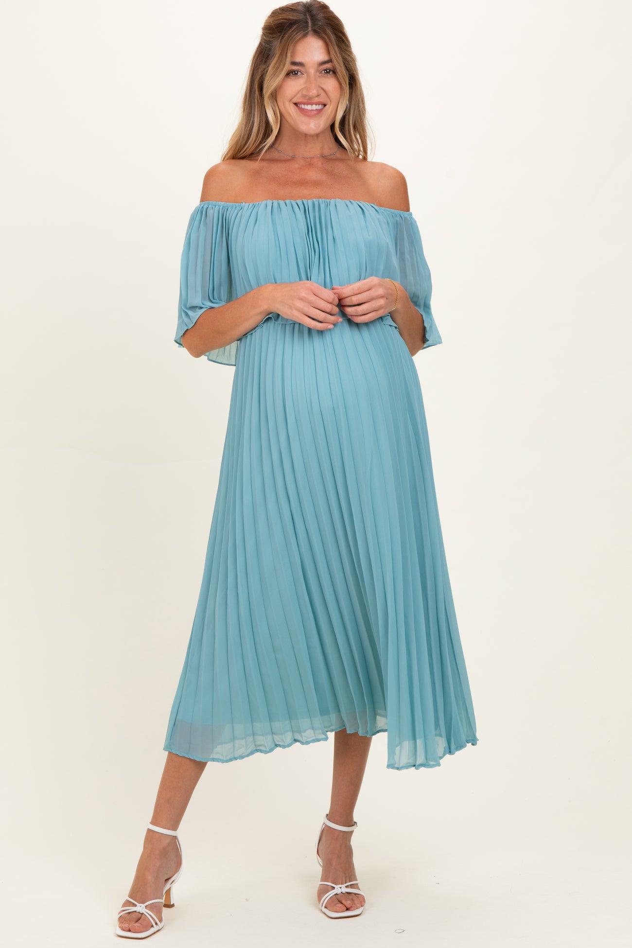 woman wearing a light teal off-the-shoulder pleated maternity dress with flowing sleeves and a comfortable fit