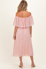 woman wearing a light pink off-the-shoulder maternity dress with pleated details, showing a pregnant baby bump from the back