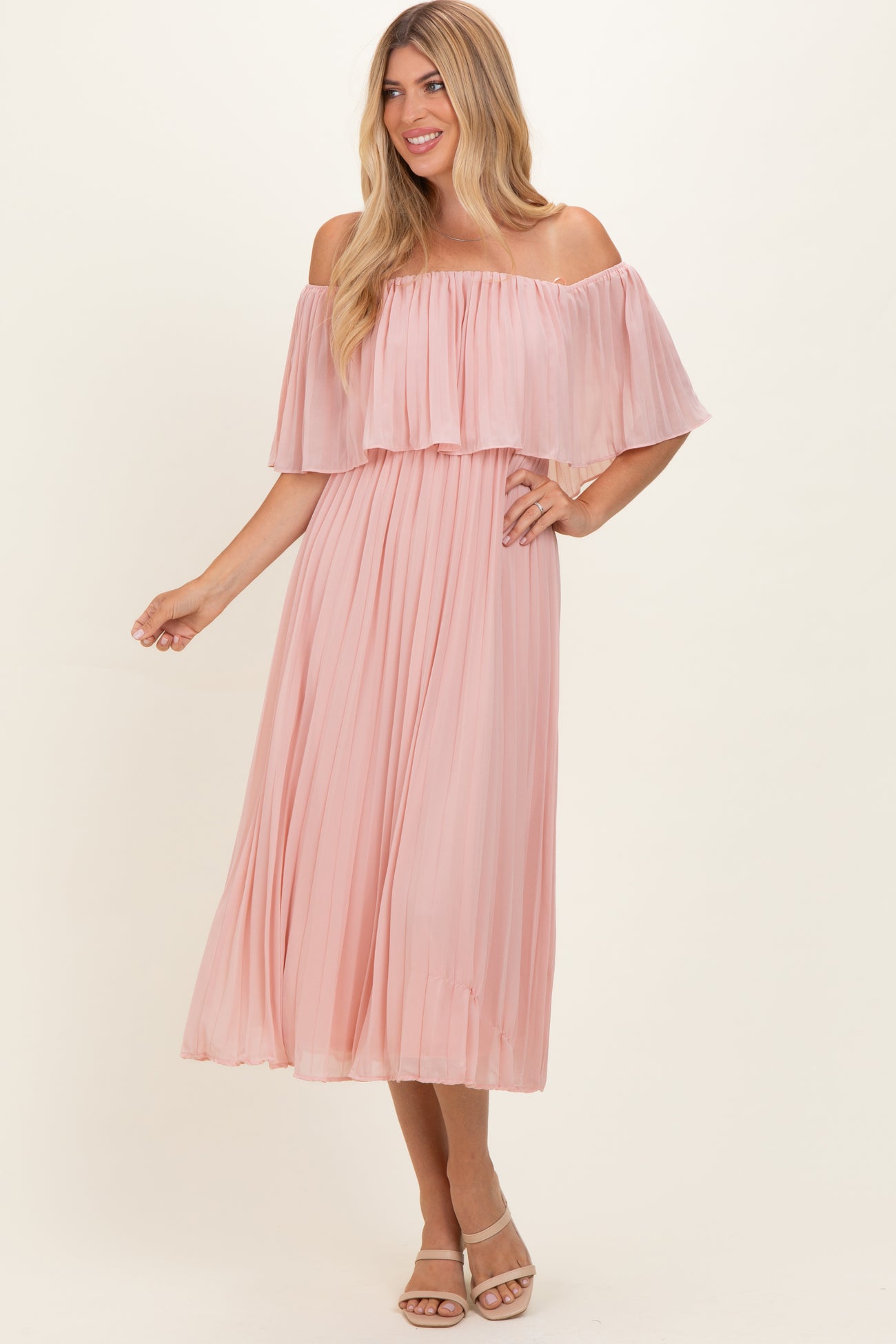 woman wearing a blush pink off-the-shoulder pleated maxi dress with a flowing silhouette