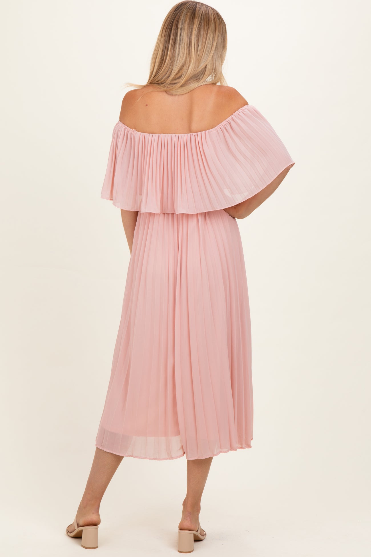 woman wearing a light pink off-the-shoulder pleated dress, shown from the back