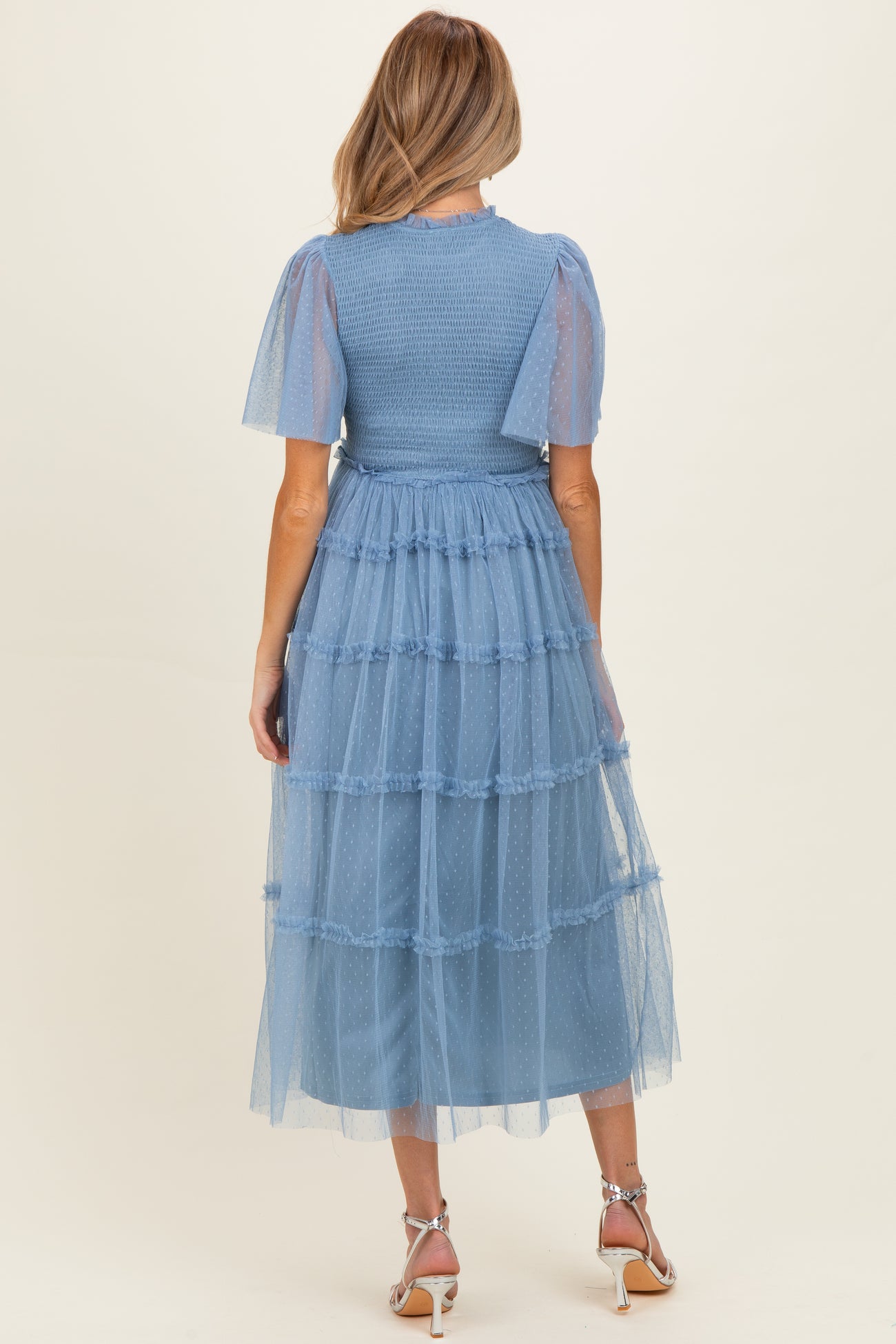 woman wearing a light blue maternity dress with puff sleeves and tiered tulle skirt, showcasing a flowing design
