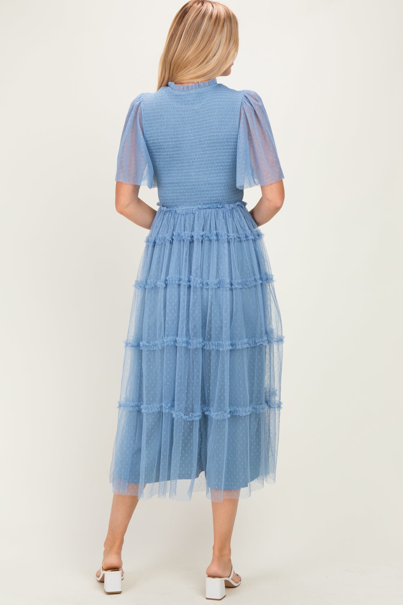 woman wearing a blue tiered midi dress with tulle puff sleeves and a fitted bodice, shown from the back