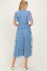 woman wearing a blue tiered midi dress with tulle puff sleeves and a fitted bodice, shown from the back