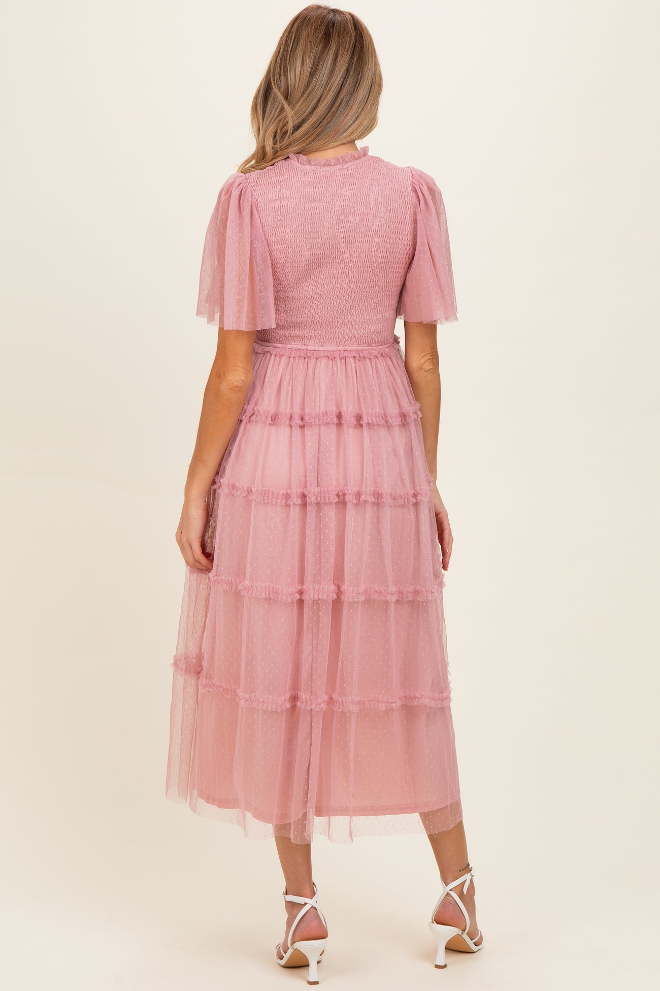 woman wearing a pink tiered maternity dress with short puff sleeves and a smocked bodice