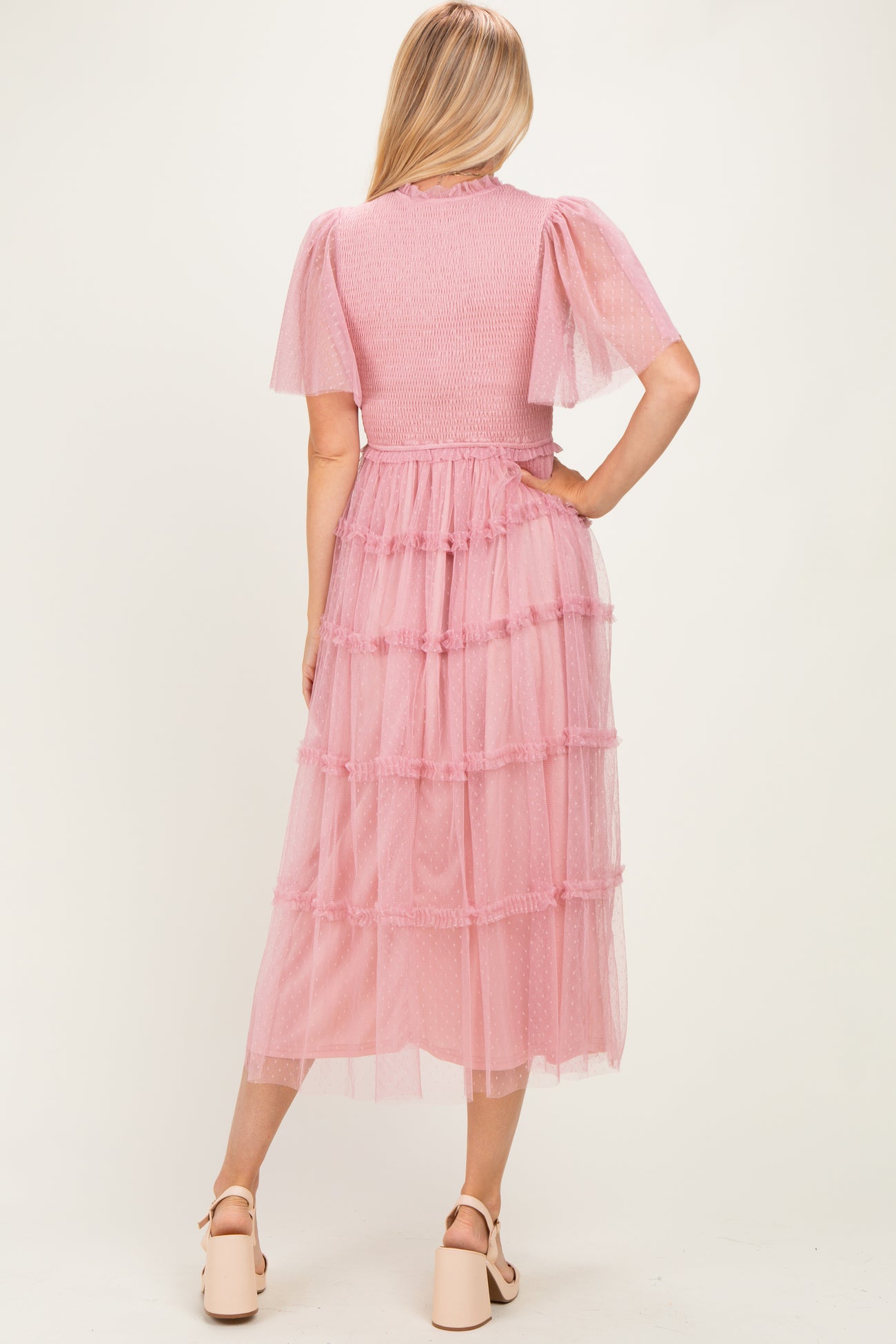 woman wearing a pink tiered tulle maxi dress with short flutter sleeves, seen from the back