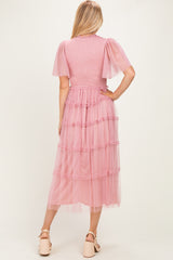 woman wearing a pink tiered tulle maxi dress with short flutter sleeves, seen from the back