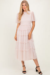 woman wearing a pink tiered tulle midi dress with short puff sleeves and a smocked bodice