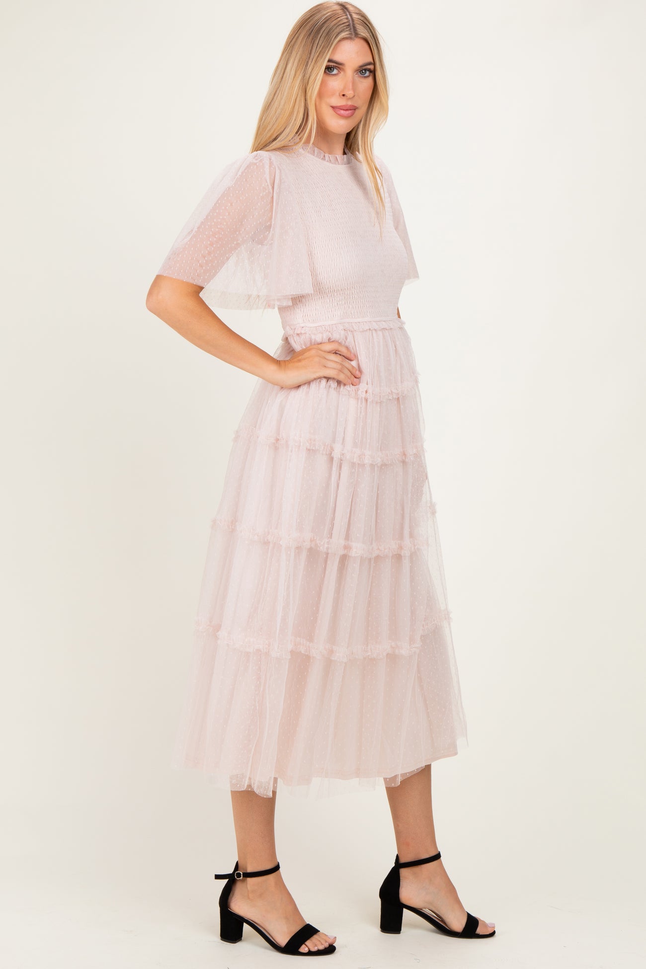 woman wearing a blush pink tiered tulle midi dress with short puff sleeves and a fitted bodice