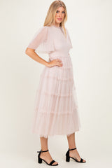 woman wearing a blush pink tiered tulle midi dress with short puff sleeves and a fitted bodice