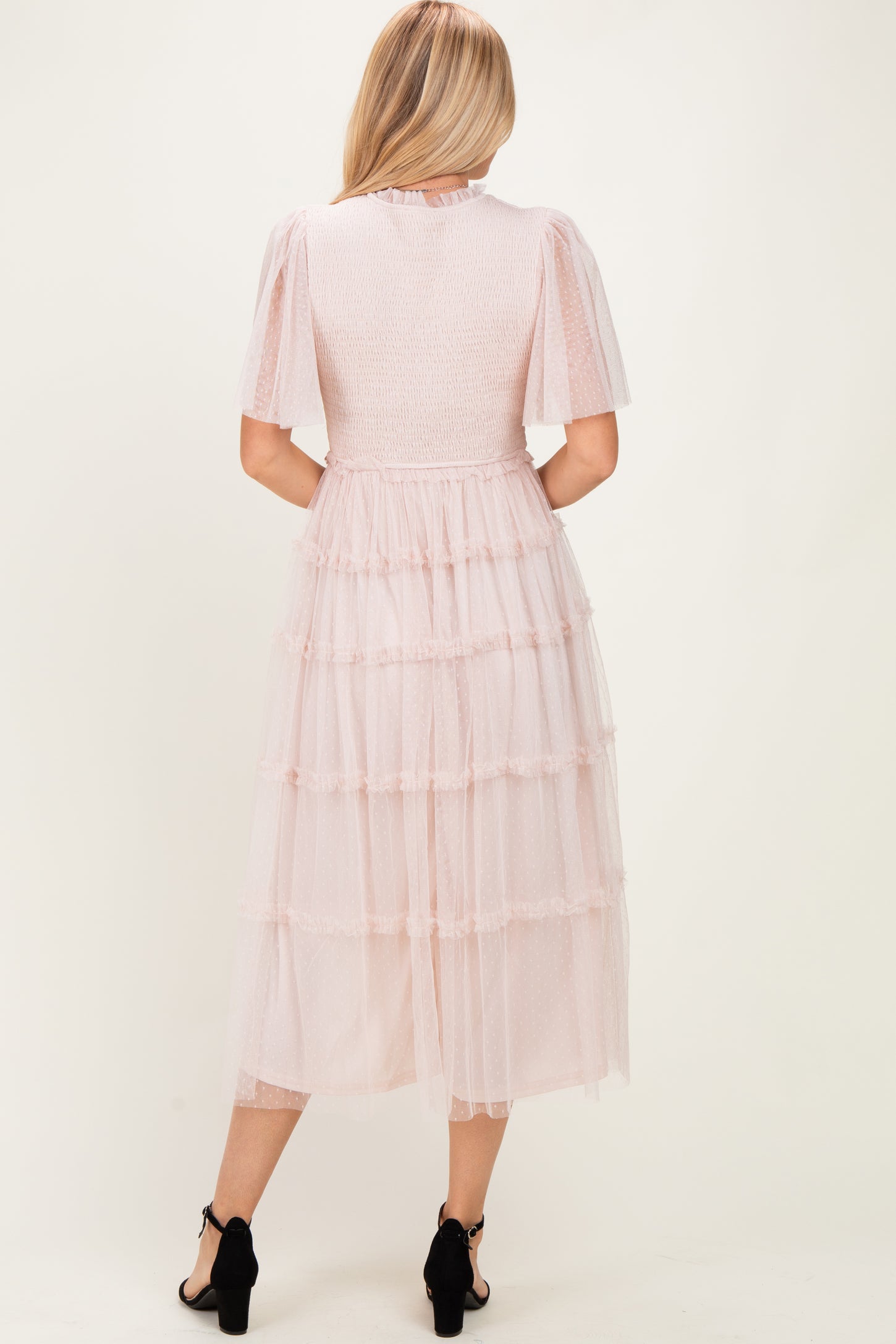 woman wearing a light pink tiered tulle midi dress with short puff sleeves and a fitted bodice