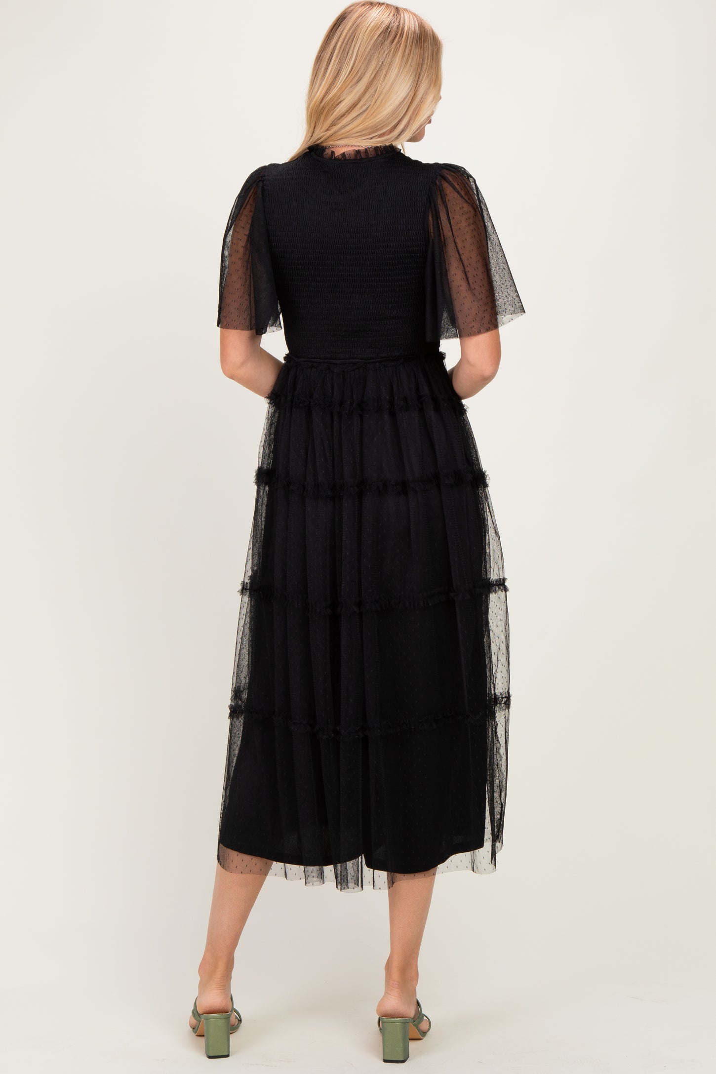 woman wearing a black tiered tulle dress with short sleeves, viewed from the back, showcasing a flowy silhouette