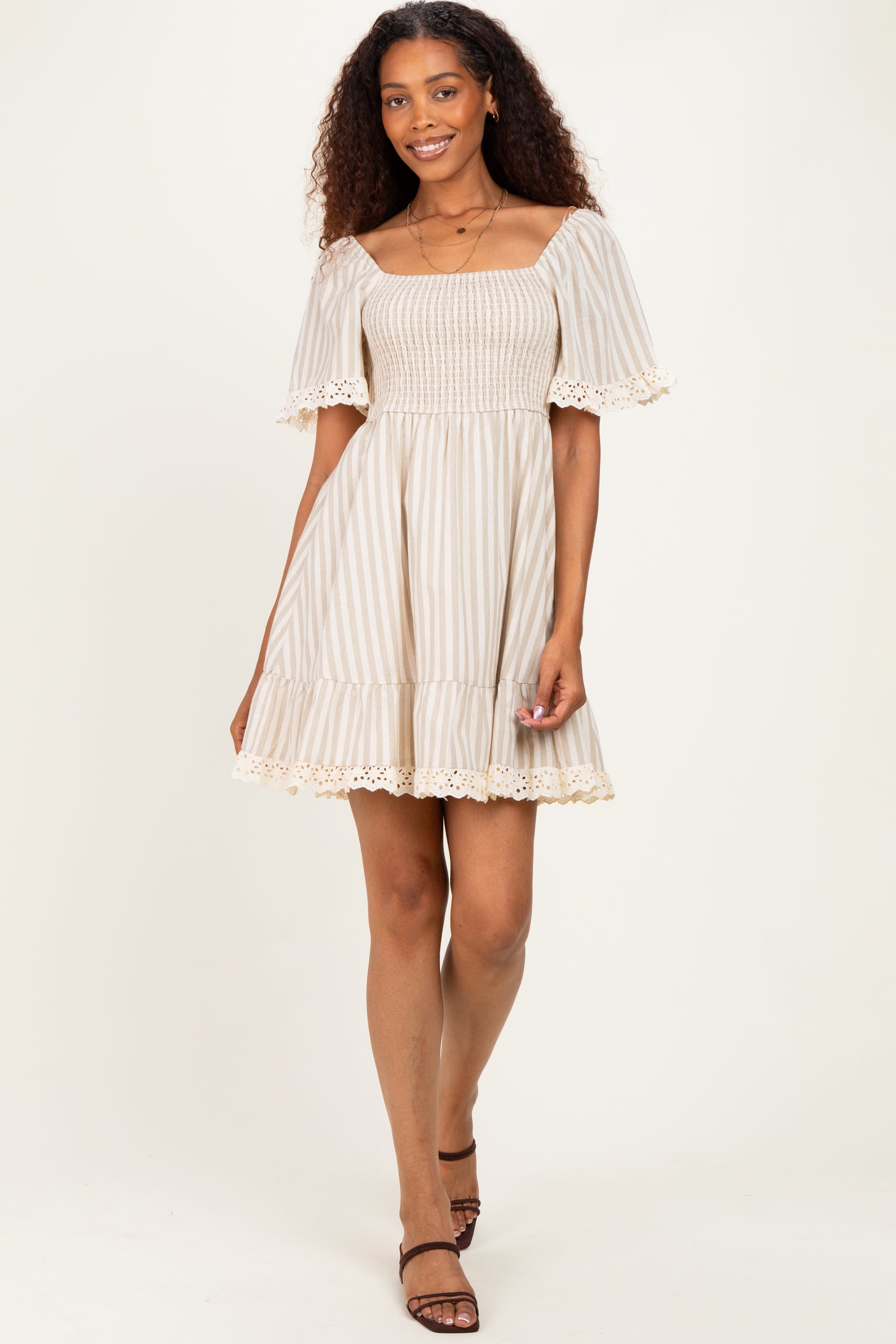 woman wearing a cream and beige striped off-the-shoulder dress with smocking and lace trim