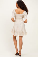 woman wearing a beige and white striped mini dress with short puff sleeves and lace trim on the hem