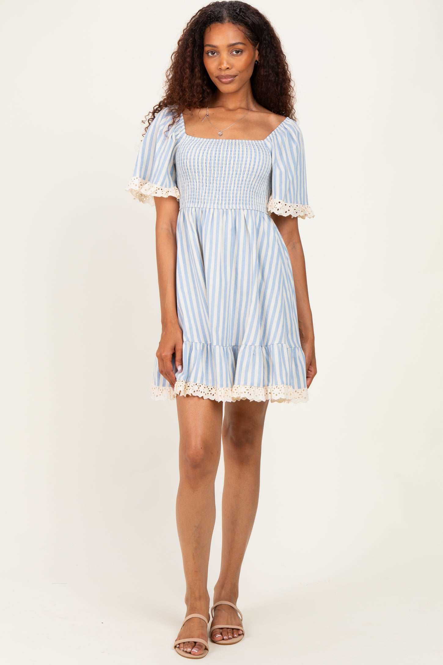 woman wearing a blue and white striped smocked dress with lace trim details and short sleeves