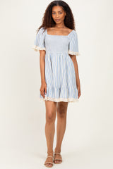 woman wearing a blue and white striped smocked dress with lace trim details and short sleeves