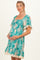 woman wearing a teal floral print maternity dress with smocked bodice and lace trim, cradling her baby bump