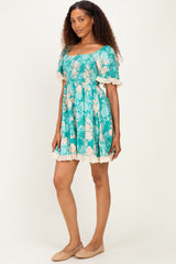 woman wearing a turquoise floral print short puff sleeve dress with lace trim details