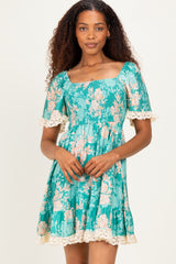 woman wearing a teal floral dress with short puff sleeves and lace trim