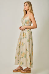 woman wearing a beige floral maxi dress with a fitted bodice and flowy skirt, standing in profile