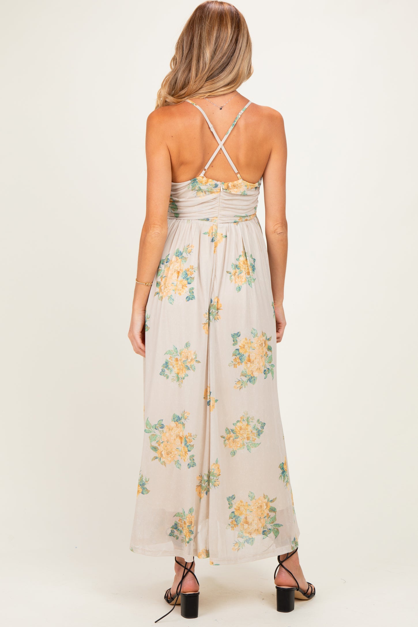 woman wearing a floral print maternity maxi dress with a crisscross back and gathered waist, showing her baby bump