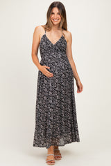 woman wearing a black floral maternity maxi dress and holding her baby bump