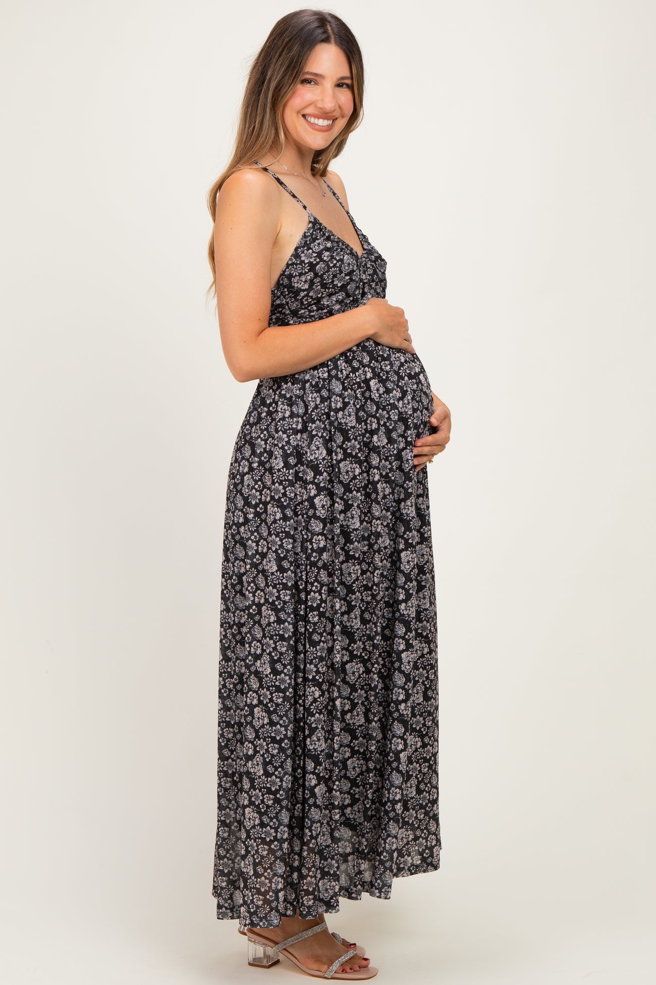 woman wearing a black floral maternity maxi dress and holding her baby bump