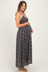 woman wearing a black floral maternity maxi dress and holding her baby bump