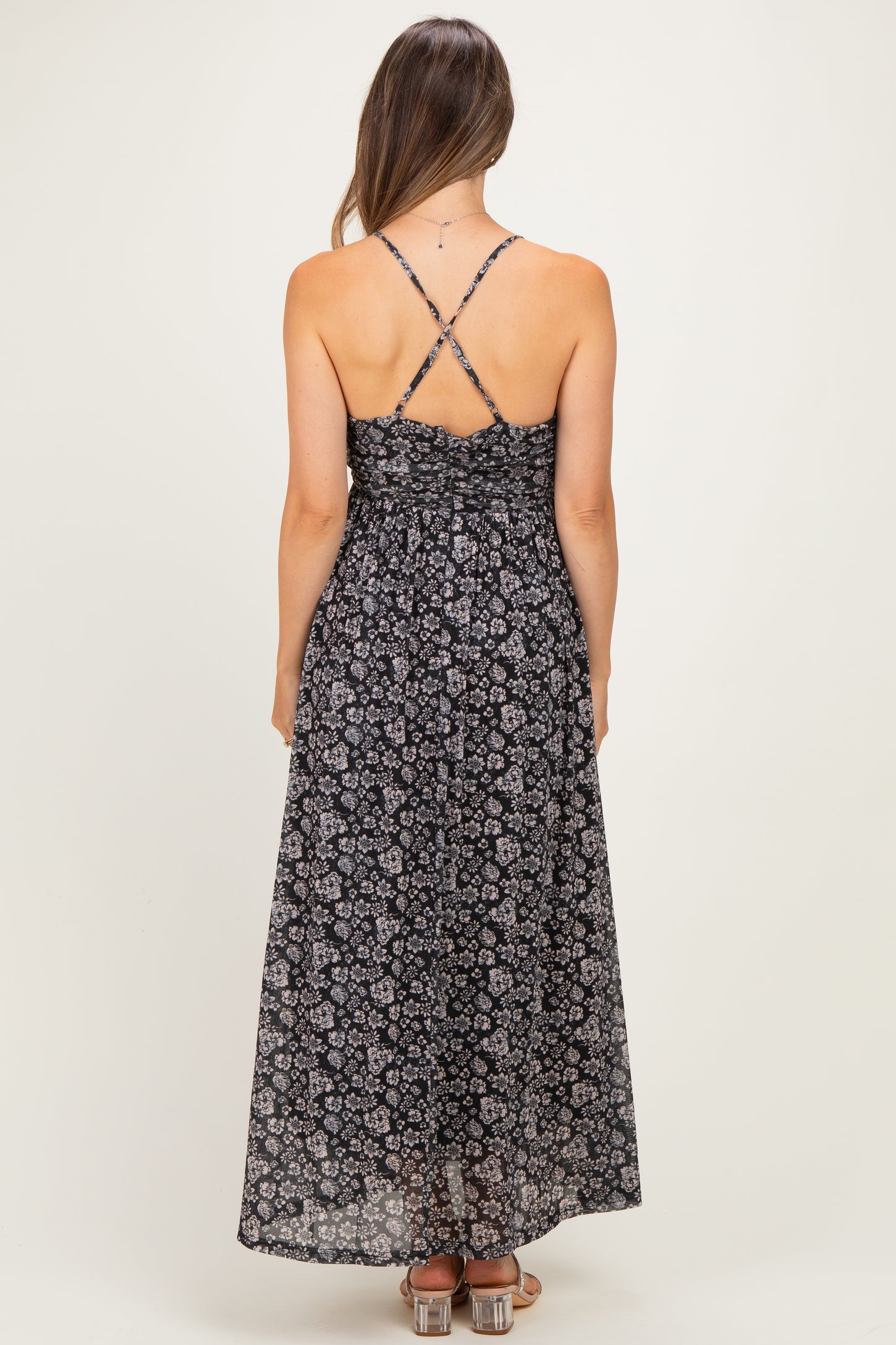 woman wearing a black floral print maternity maxi dress with adjustable cross-back straps