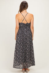 woman wearing a black floral print maternity maxi dress with adjustable cross-back straps